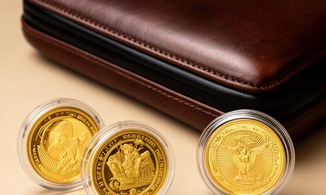 Gouden Maple Leaf en Krugerrand munten in beschermende capsules naast een leren etui